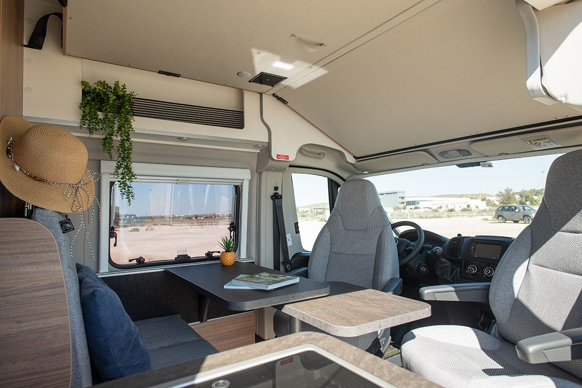 “Interior del salón de la Weinsberg Carabus 600DQ Hot Edition con mesa central y asientos enfrentados.”